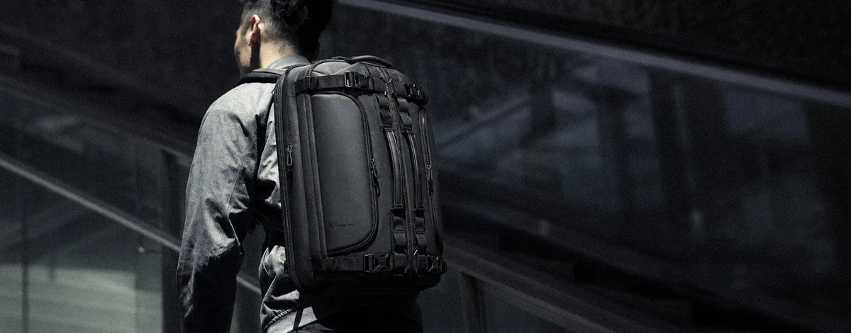 Man carrying a black Cinomadist travel backpack in a modern city