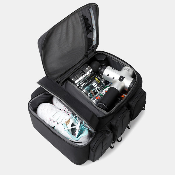 Black travel bag with compartments containing a white sneaker, black and silver bottle, and other items on a light gray background.#color_black