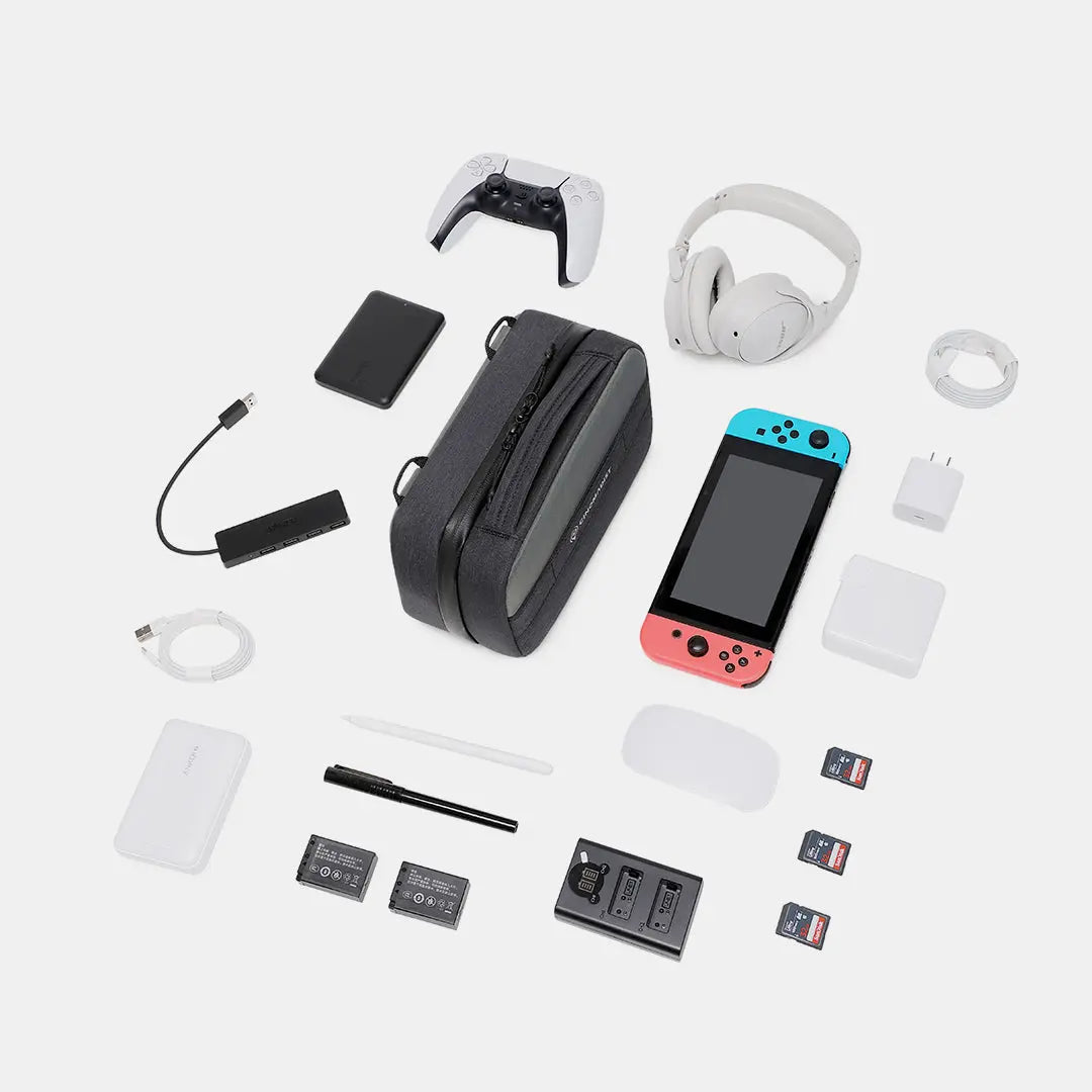 Flatlay of Cinomadist Tech Pouch with travel gear including gaming devices, adapters, and memory cards#color_black