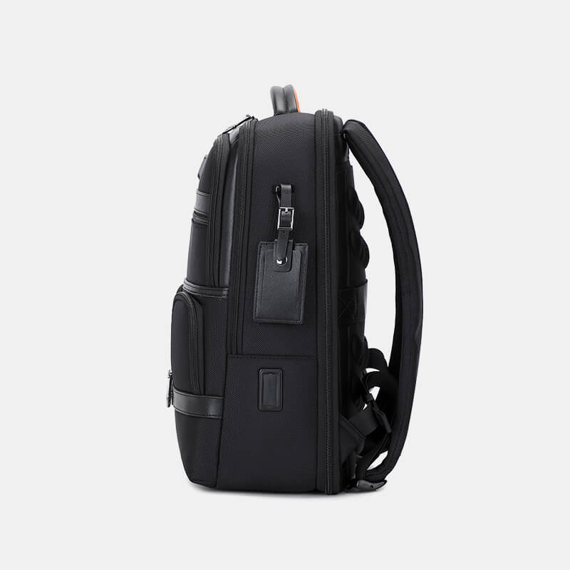 Black backpack with multiple pockets and zippers on a light gray background