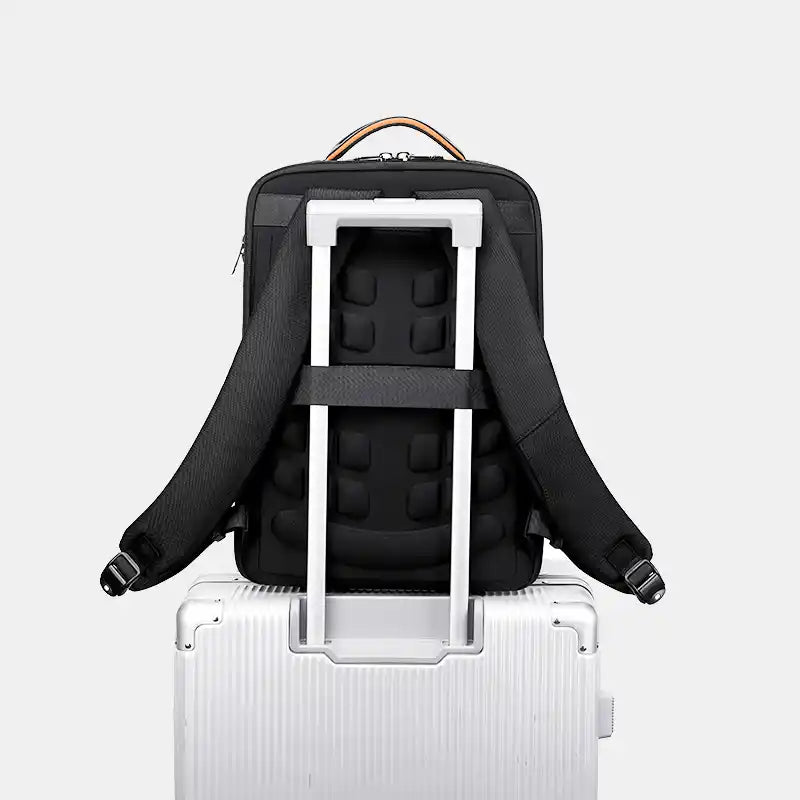Black backpack with a white frame on top of a silver suitcase against a light gray background