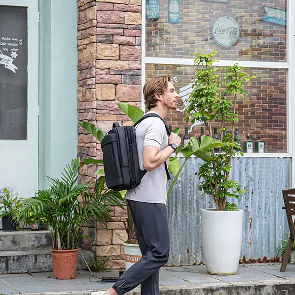 Back view of man walking with Cinomadist backpack in a casual urban setting