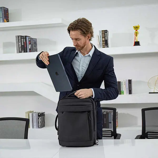 Businessman using laptop from Cinomadist backpack in a modern office