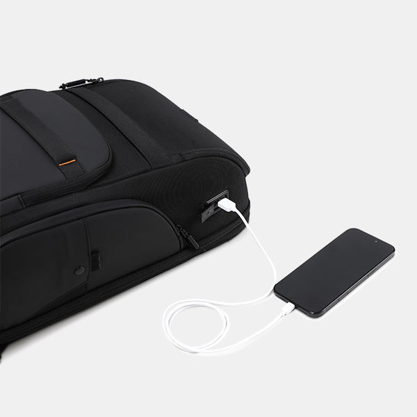 Black backpack with a USB port charging a smartphone on a light gray background