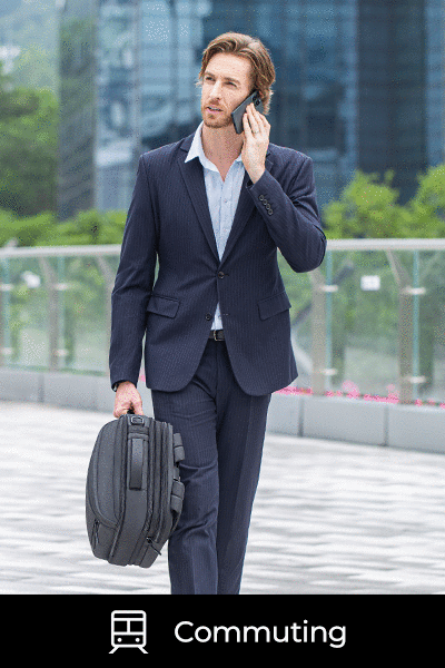 A businessman holding a sleek laptop backpack in one hand while having a phone conversation, showcasing the bag's portable design and professional style.