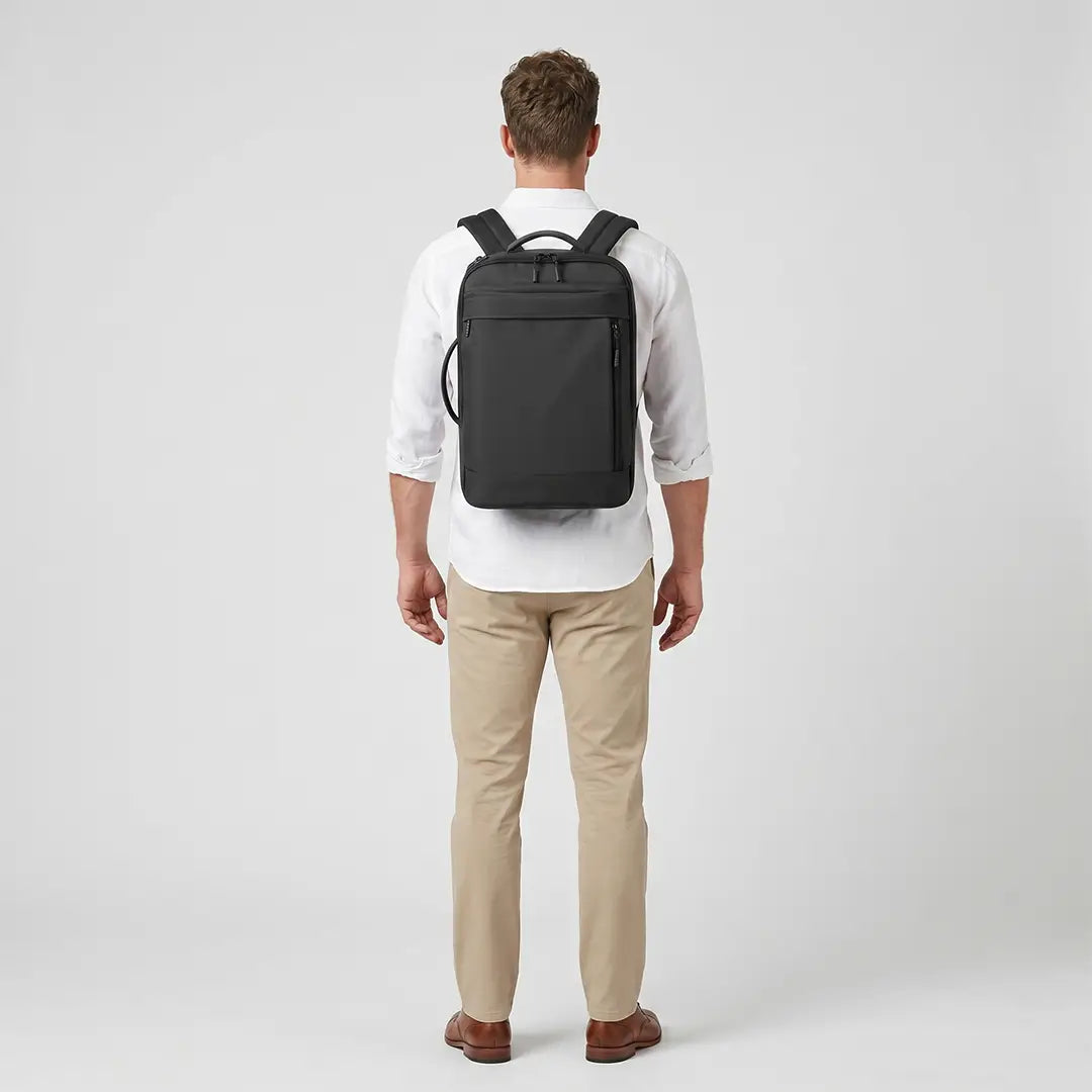 Rear view of a traveler wearing the minimalist black Travel Expandable Backpack Pro featuring technical synthetic fabrics.