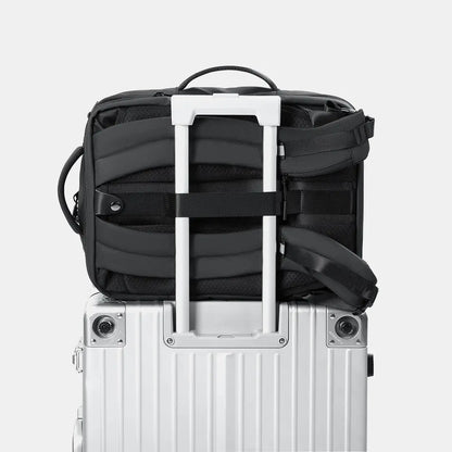 Close-up of the backpack's rear panel secured tightly to a rolling suitcase handle using the dedicated luggage pass-through strap.