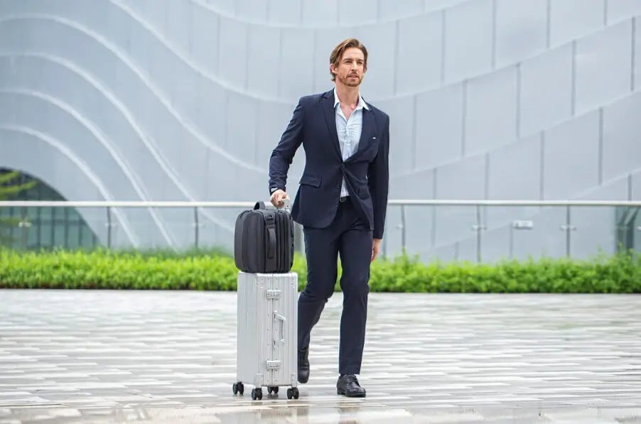 Man in a suit pulling two suitcases on a city street