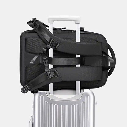 Black travel bag with straps on a silver suitcase against a white background