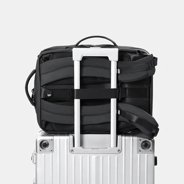 ravel-friendly Cinomadist backpack securely attached to a rolling suitcase via luggage strap.