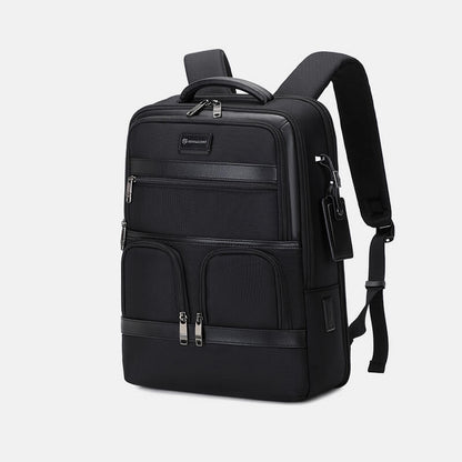 Black backpack with multiple pockets and zippers on a light gray background