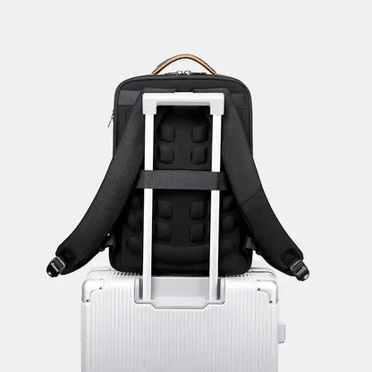 Black backpack with a white frame on top of a silver suitcase against a light gray background