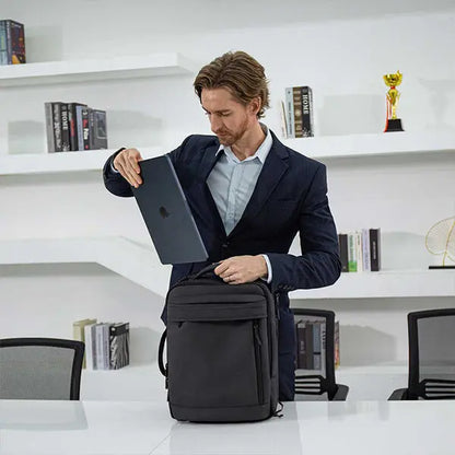 Businessman using laptop from Cinomadist backpack in a modern office