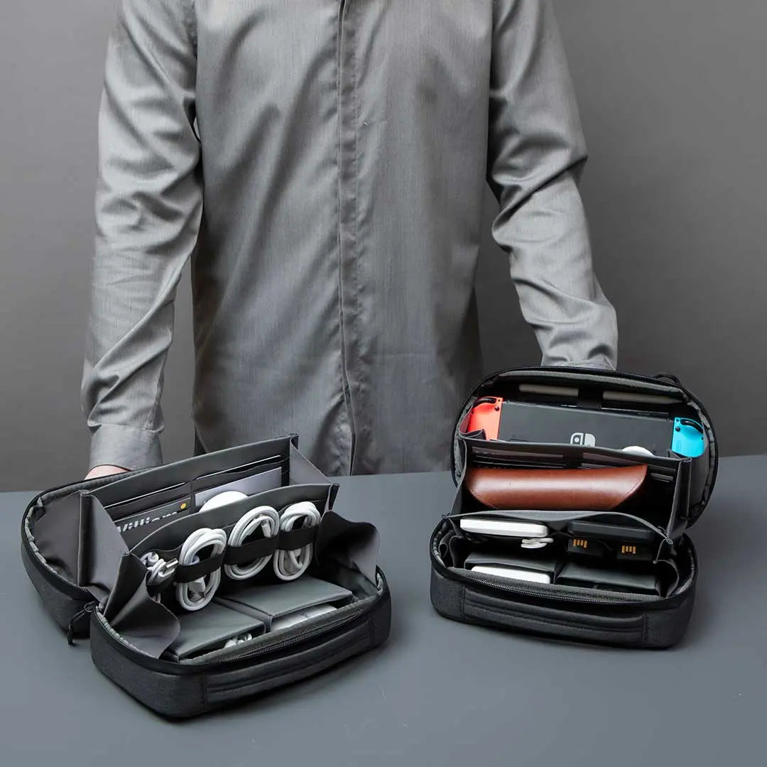 Compact Cinomadist tech pouch held by traveler, packed with gadgets like razors, chargers, and accessories.#color_black