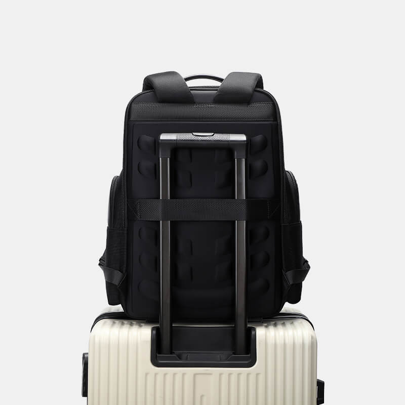 Black backpack with rolling handle on a white suitcase against a light gray background
