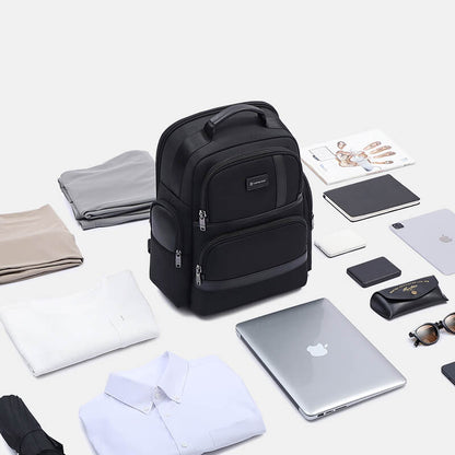 Black backpack surrounded by various items on a light background