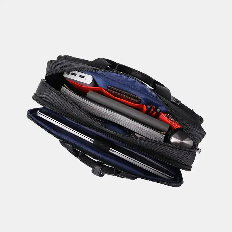 Black laptop bag with compartments containing a tablet, notebook, and other items on a light gray background