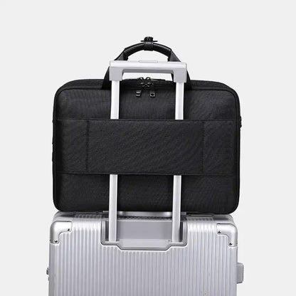 Black travel bag with handle on top of a silver suitcase