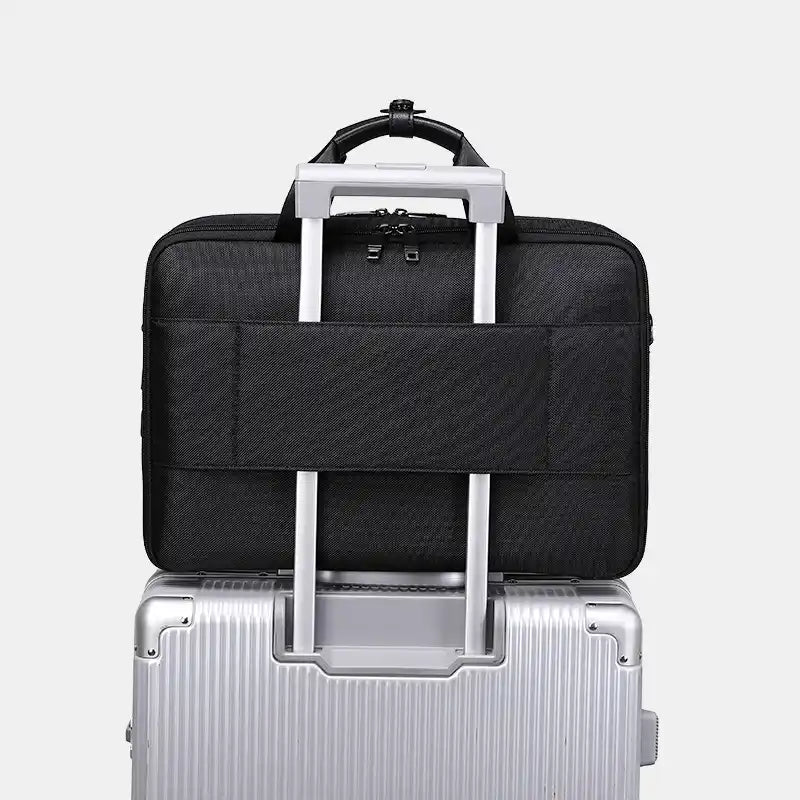 Black travel bag with handle on top of a silver suitcase