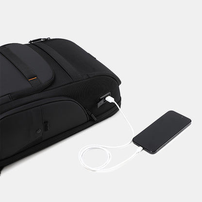 Black backpack with a USB port charging a smartphone on a light gray background