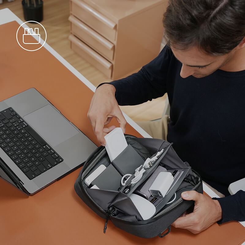 A man opens his digital organizer bag, neatly arranged inside with a charger ready to be used.