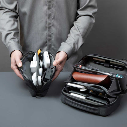 A person vertically organizing gadgets and cables inside a Cinomadist slim tech pouch with dual compartments.