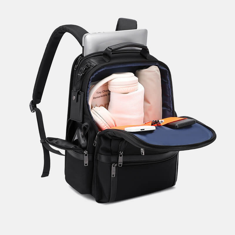 Black backpack with compartments containing a laptop, books, and electronic devices on a light gray background