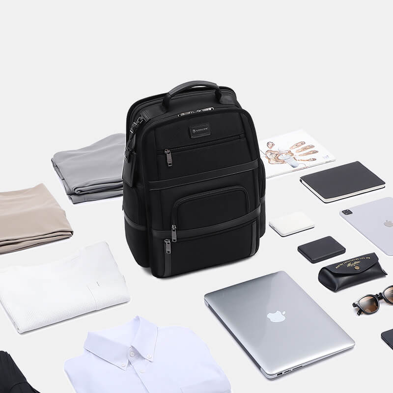 Black backpack surrounded by various items on a light background