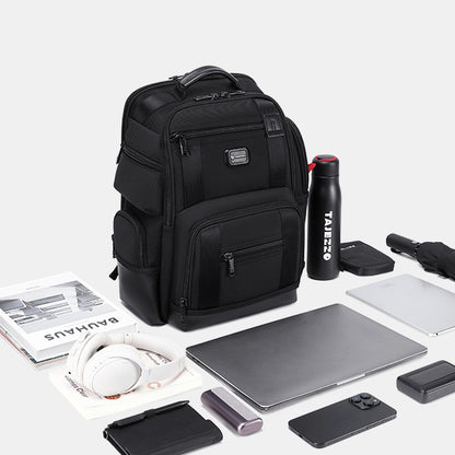 Black backpack with laptop, water bottle, and other items on a white background